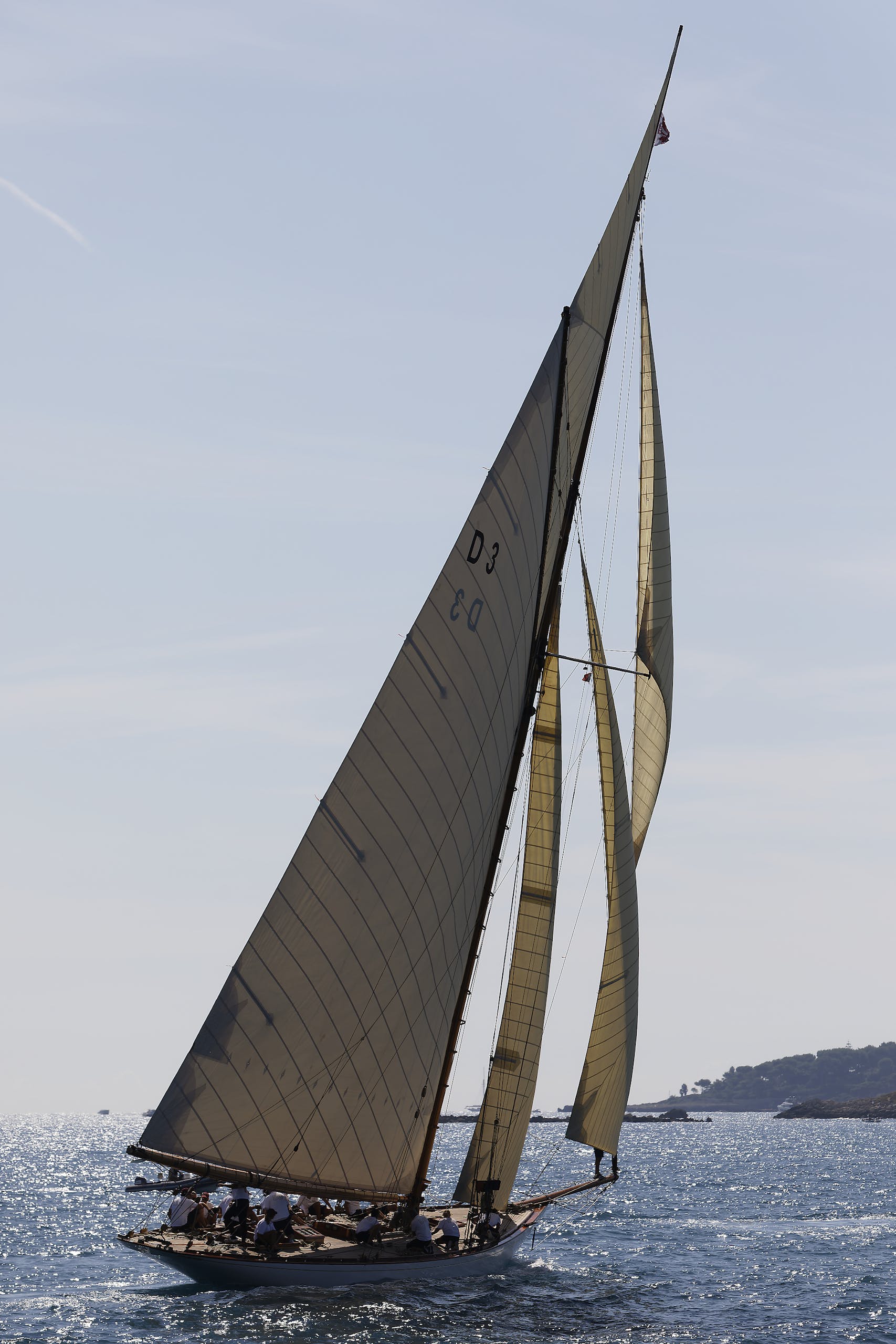 Classic yacht gracefully sailing under clear skies in a picturesque seascape.